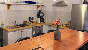 A modern kitchen with a wooden dining table, a microwave, a sink, and a refrigerator.