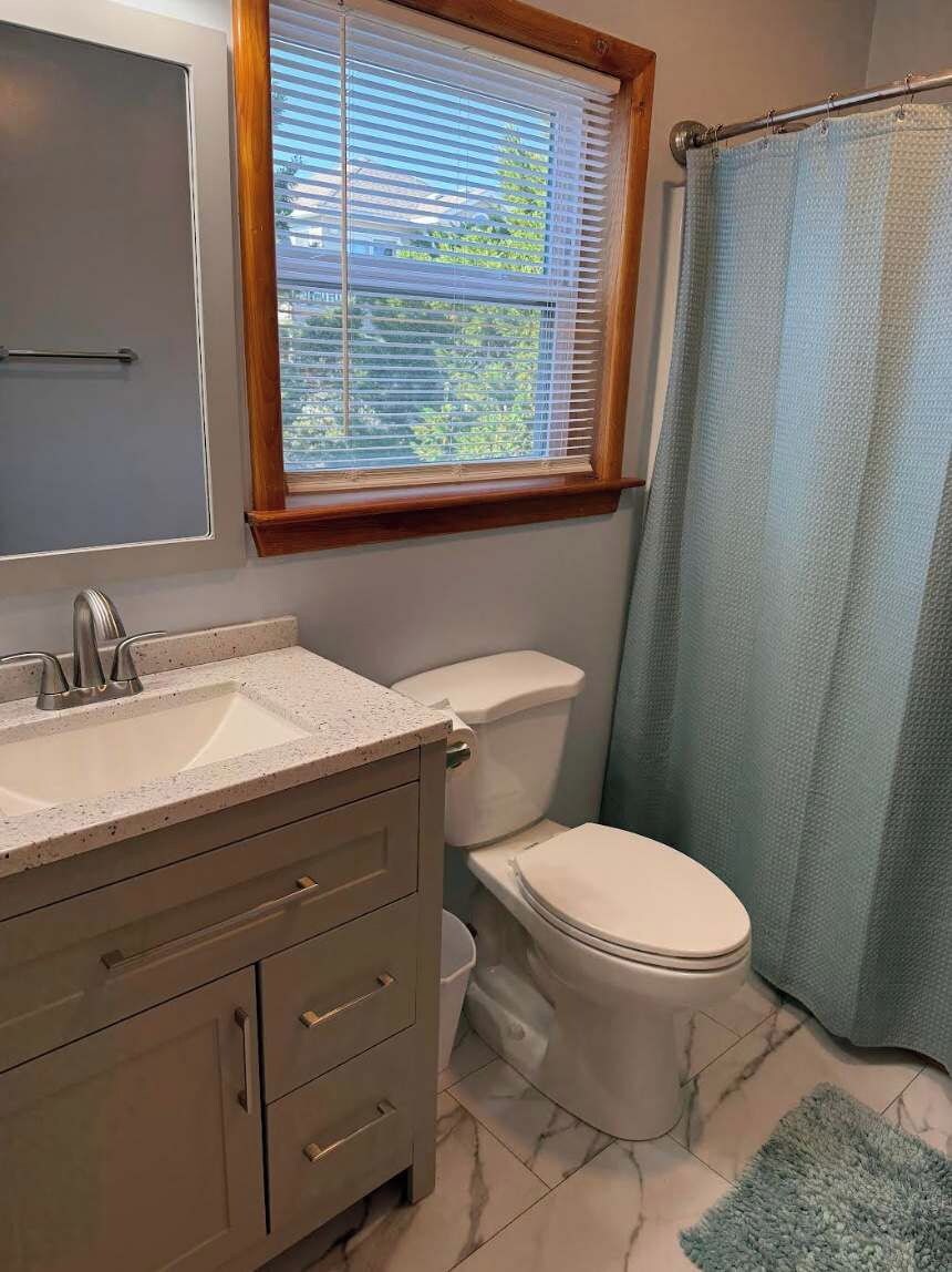 Une salle de bain avec des toilettes, un lavabo et une fenêtre.