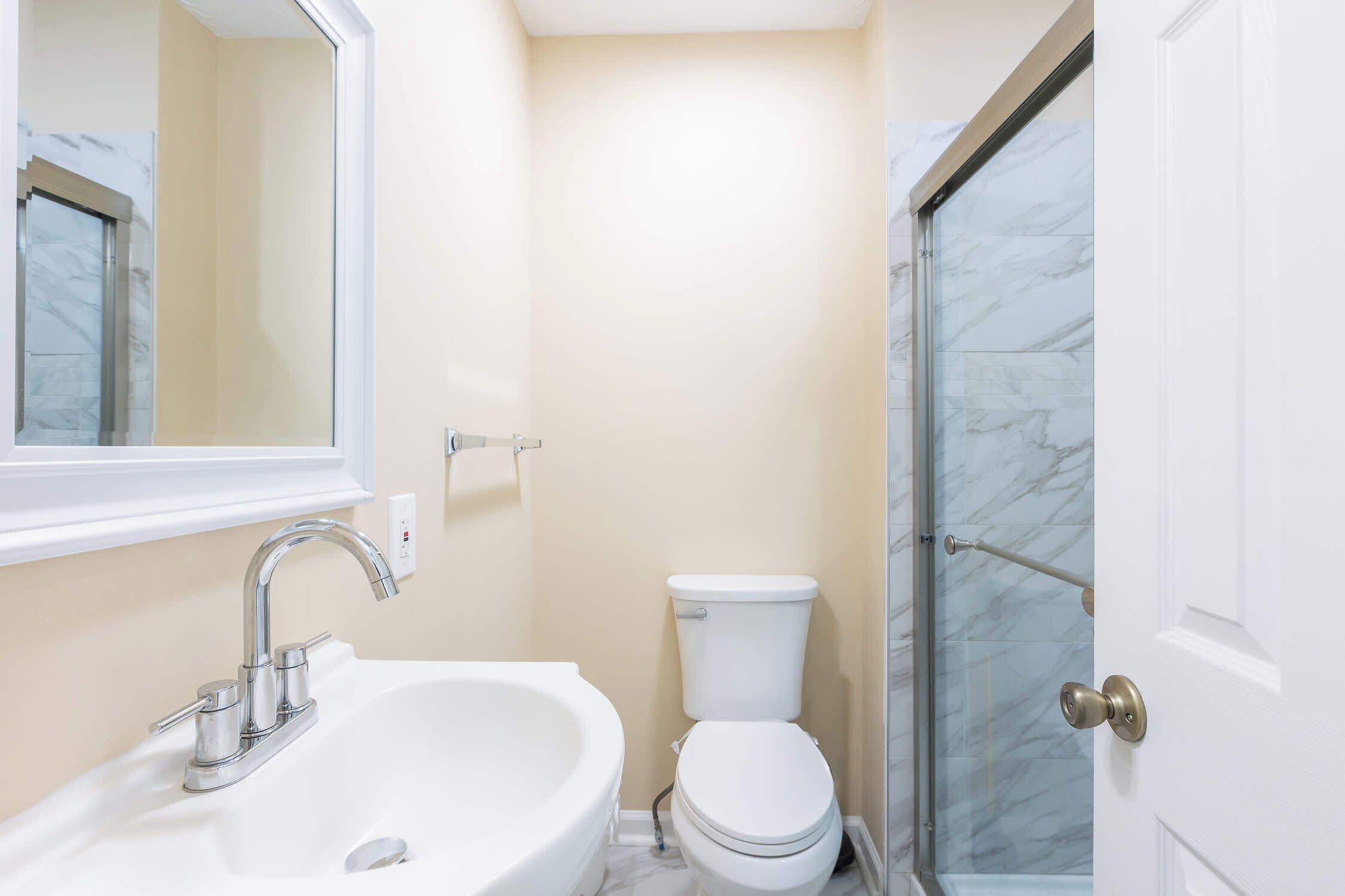 Un baño con lavamanos blanco, inodoro y cabina de ducha de vidrio.