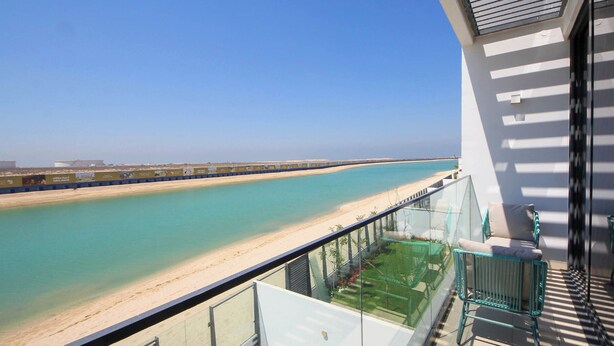 A balcony with a view of a beach and a clear sky. - Silk Valley-4B with Private Beach Access (Al Hamriya)