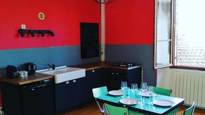 A compact kitchen with a modern design, featuring a central island, a sink, and a dining area with chairs and a table set for four. - Welcome to this large, elegant apartment. (Brioude)
