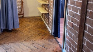 A room with a herringbone wooden floor, brick wall, and a mirror with a wooden frame. - Welcome to this large, elegant apartment. (Brioude)