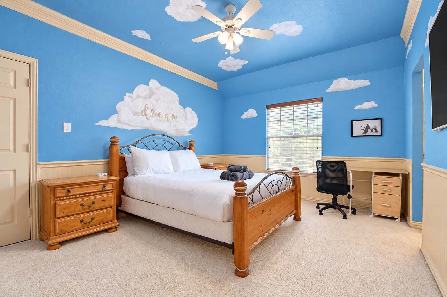 A bedroom with a bed, wooden nightstands, a desk, and a chair.