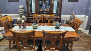 A dining room with a wooden table and chairs, a decorative mirror, and a statue.