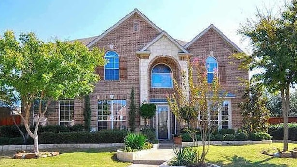 A two-story house with a brick facade, a central arched window, and a symmetrical design.