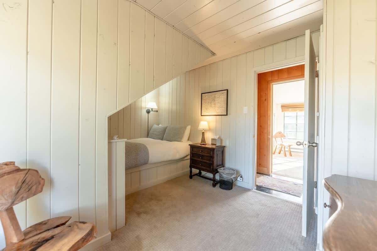 A bedroom with a bed, nightstand, and a door leading to a balcony.
