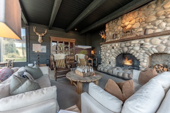 A cozy living room with a stone fireplace, leather sofas, and a wooden coffee table.