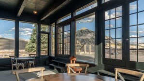 A room with large windows, a wooden table, and a bench. - The Steakhouse (Crested Butte)