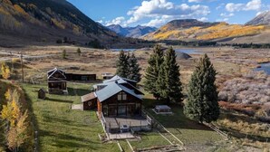 A lodge with a large deck, multiple cabins, and a scenic mountain backdrop. - The Steakhouse (Crested Butte)