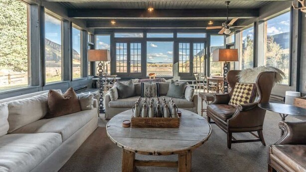 A spacious living room with a large window, a round coffee table, and a sofa. - The Steakhouse (Crested Butte)