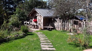 A rustic wooden house with a metal roof, surrounded by a wooden fence and various garden decorations. - Studio Apartment 'Eifelzauber' with Shared Terrace, Wi-Fi and Air Conditioning (Greimerath)
