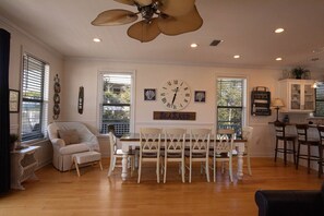 A dining area with a white table and chairs, a wall clock, and a ceiling fan.