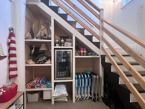 A compact storage area with shelves, a refrigerator, and exercise equipment.