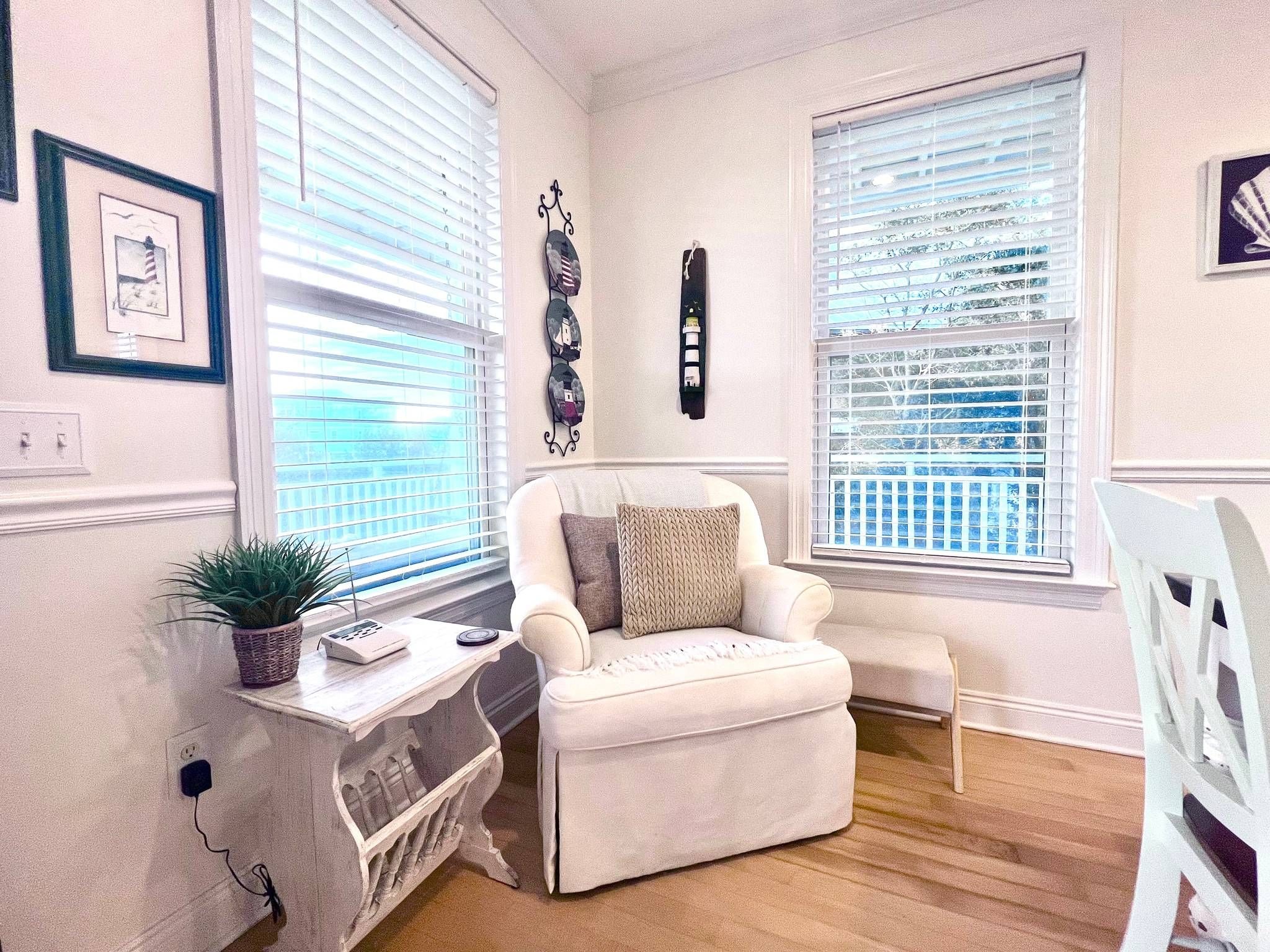 A cozy room with a white armchair, a small table with a plant, and a white chair.