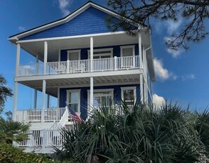 A two-story house with a balcony, surrounded by tropical plants. - Welcome to Sea Shed – Private Pool, Fire Pit, Pet Friendly (Cape San Blas)