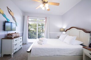 A bedroom with a bed, a dresser, a television, and a balcony with curtains. - Welcome to Sea Shed – Private Pool, Fire Pit, Pet Friendly (Cape San Blas)