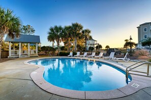 A swimming pool with lounge chairs and palm trees.