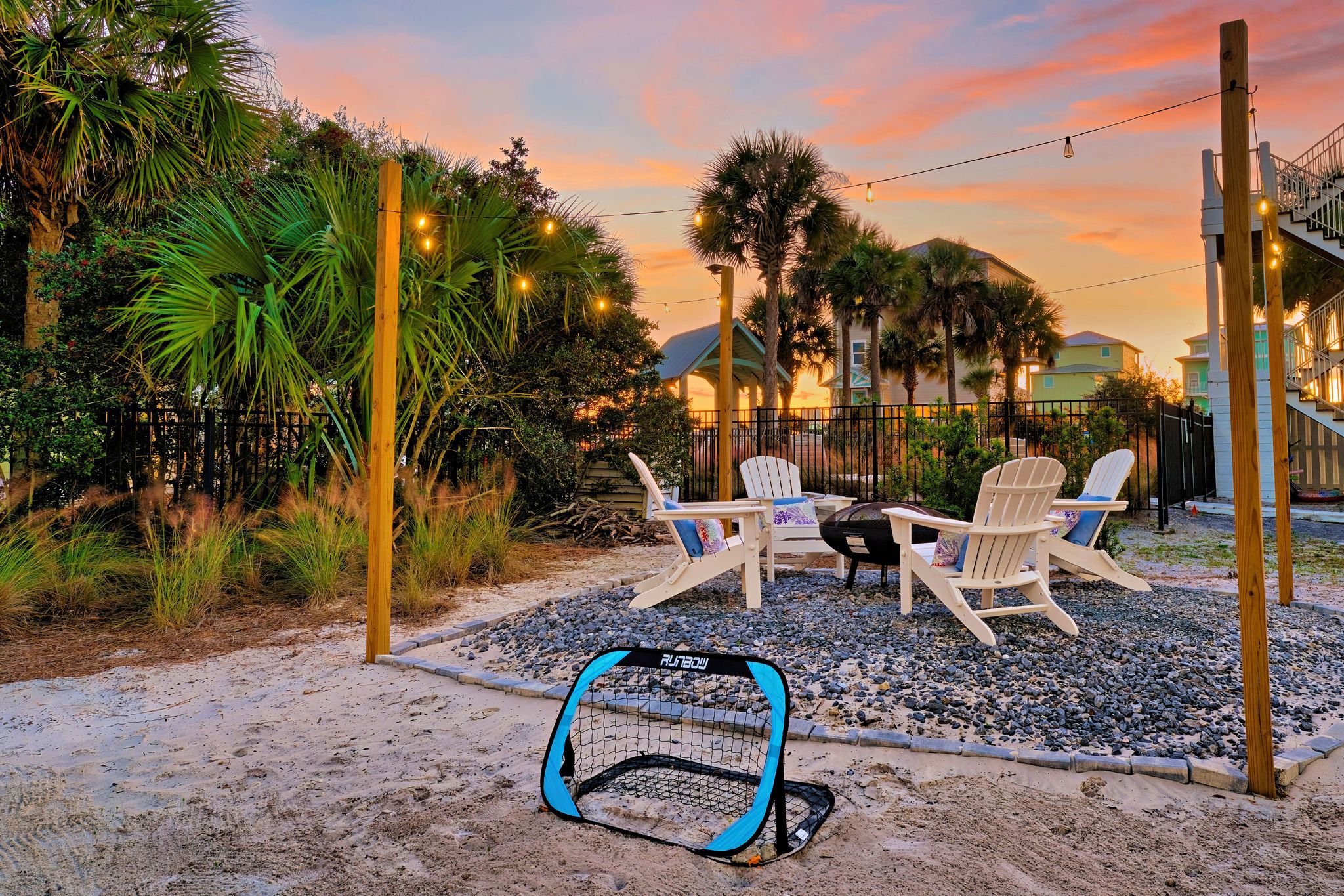A patio with two Adirondack chairs, a small table, and a blue and black playpen.