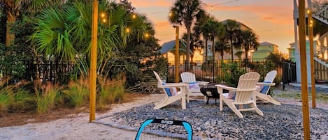 A patio with two Adirondack chairs, a small table, and a blue and black playpen.