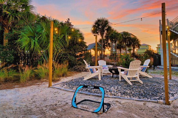 A patio with two Adirondack chairs, a small table, and a blue and black playpen.