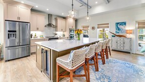 A spacious kitchen with a large island, stainless steel appliances, and a rustic ceiling. - Lulu's Beach House- Volleyball Court, North Cape (Port St Joe)