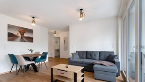 A modern living room with a sofa, a dining table with chairs, a coffee table, and a painting on the wall.