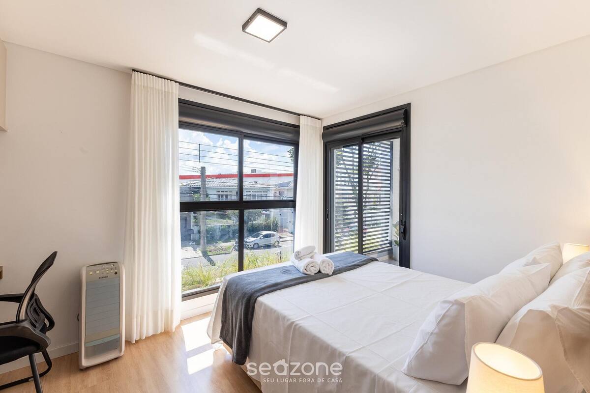 Ein Schlafzimmer mit einem Bett, einem Sessel, einem Heizgerät und einem Fenster mit Blick ins Freie.