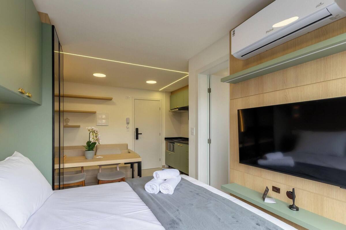Ein Hotelzimmer mit Bett, Schreibtisch, Stuhl, Fernseher und Klimaanlage.