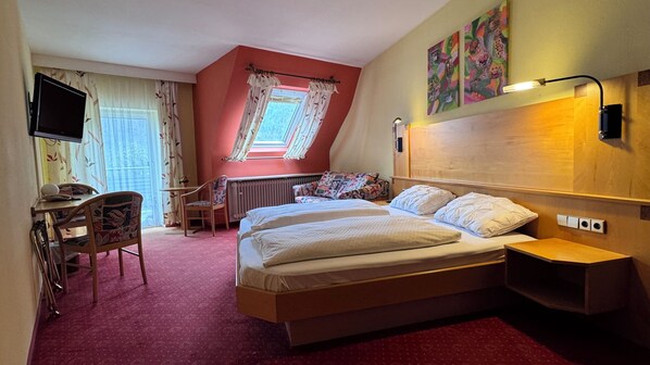 A hotel room with a bed, a desk, a chair, a radiator, and a TV. - Hotel Restaurant Freihof (Oberharmersbach)