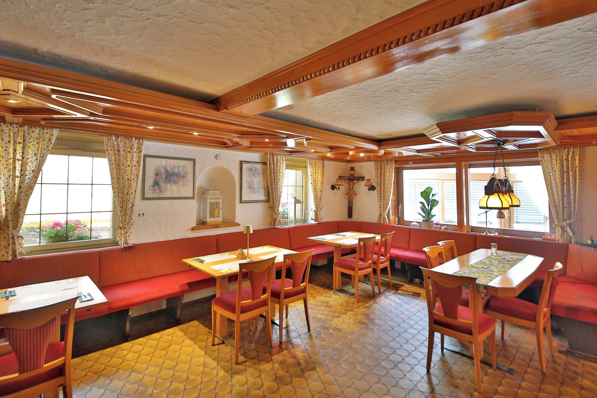 A restaurant with wooden paneling, red cushioned benches, and tables with chairs.