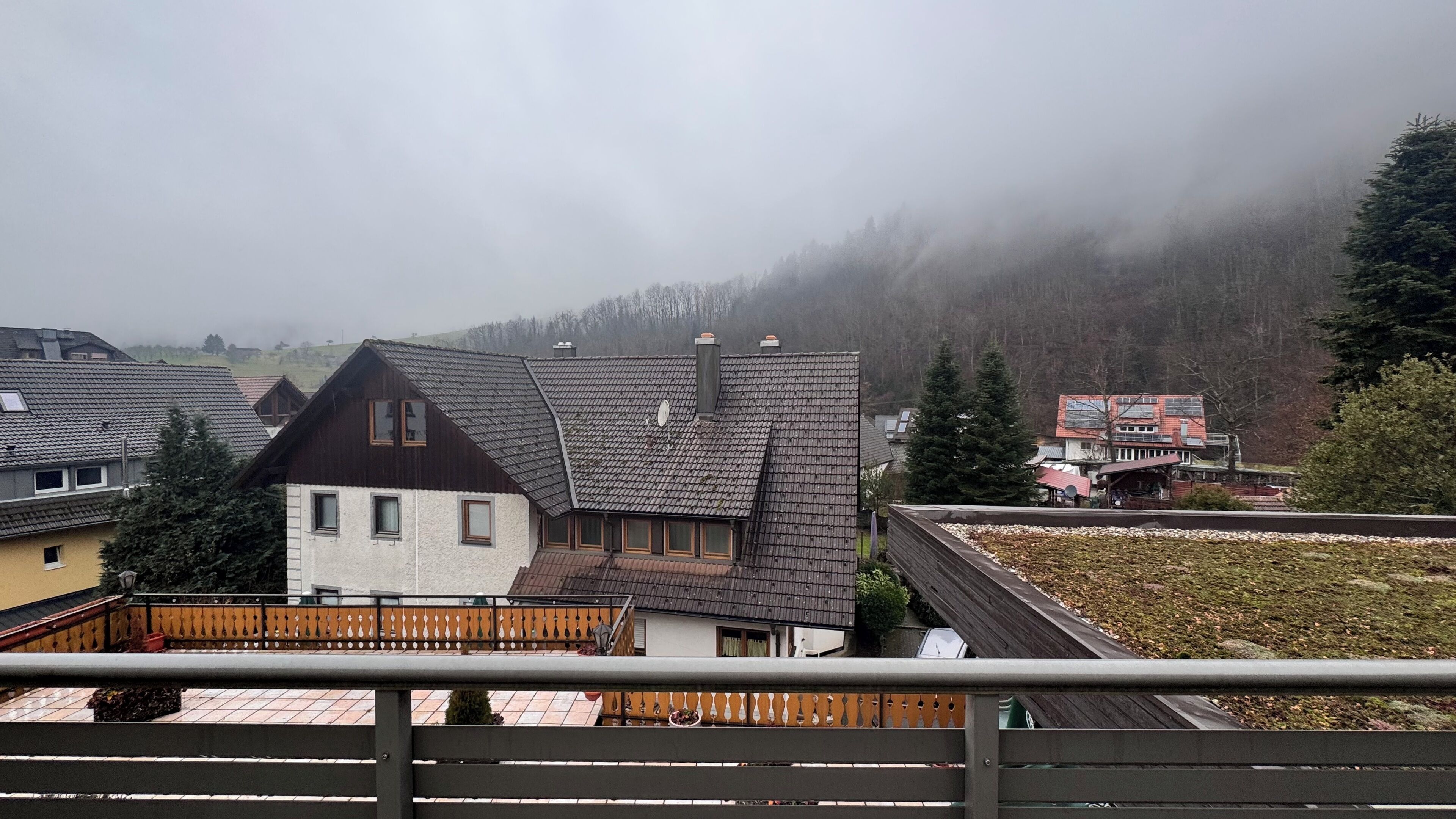 Un quartiere residenziale con case dotate di tetti spioventi e un recinto in legno in primo piano.