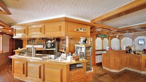 A wooden bar area with a coffee machine, a glass display case, and a reception desk. - Hotel Restaurant Freihof (Oberharmersbach)