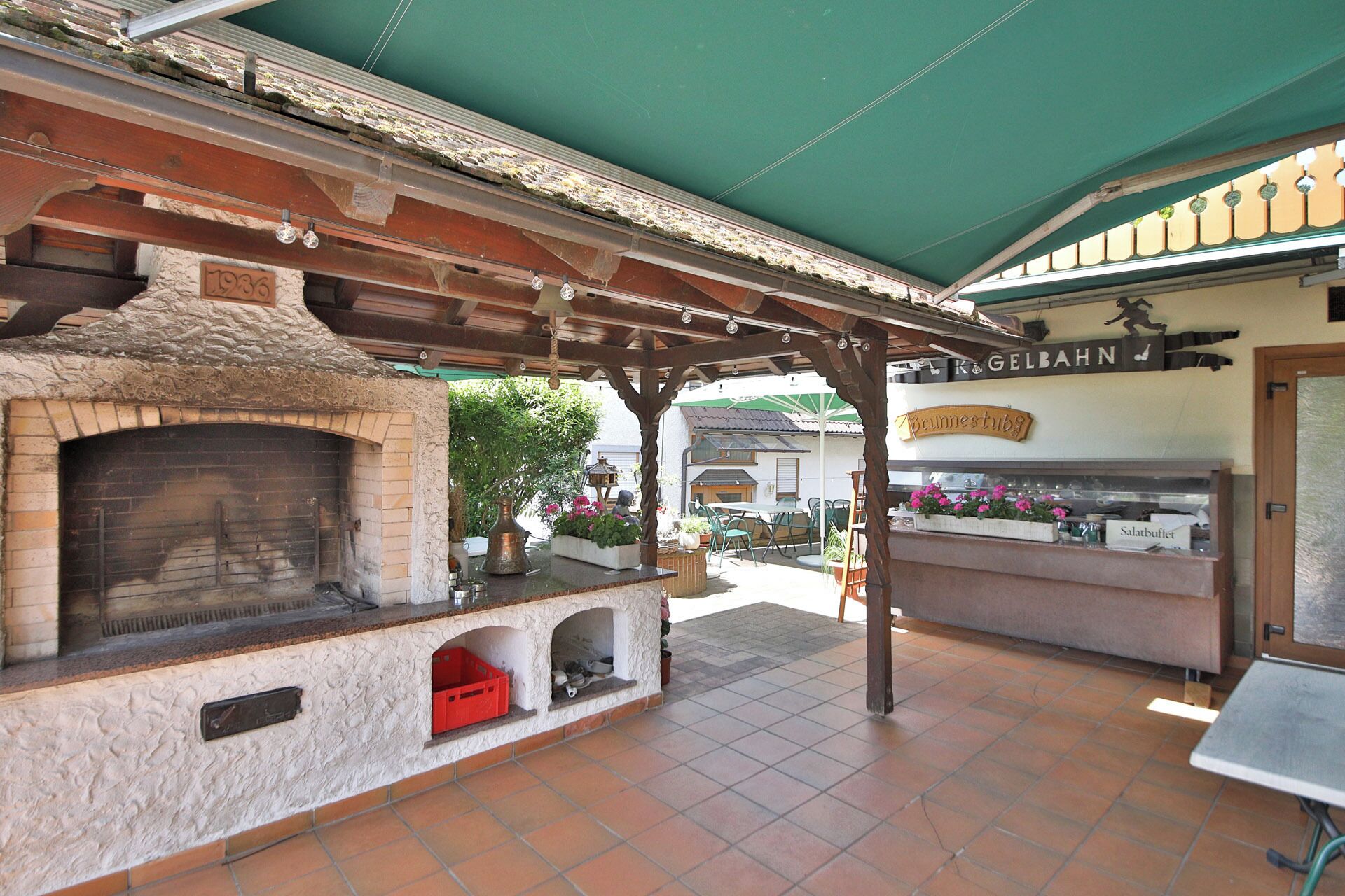 An outdoor patio area with a brick oven, seating, and a sign for 'Brunnestuben'.