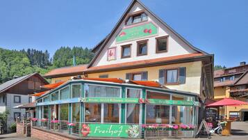 Un edificio tradicional con toldo verde, un letrero que indica que es un hotel y restaurante, y un cielo despejado.