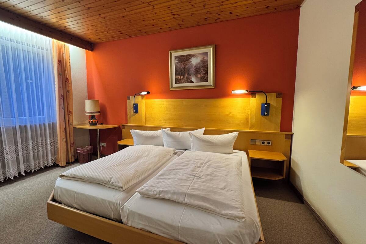 Ein Hotelzimmer mit einem großen Bett, zwei Nachttischen, einer Lampe und einem Bild an der Wand.