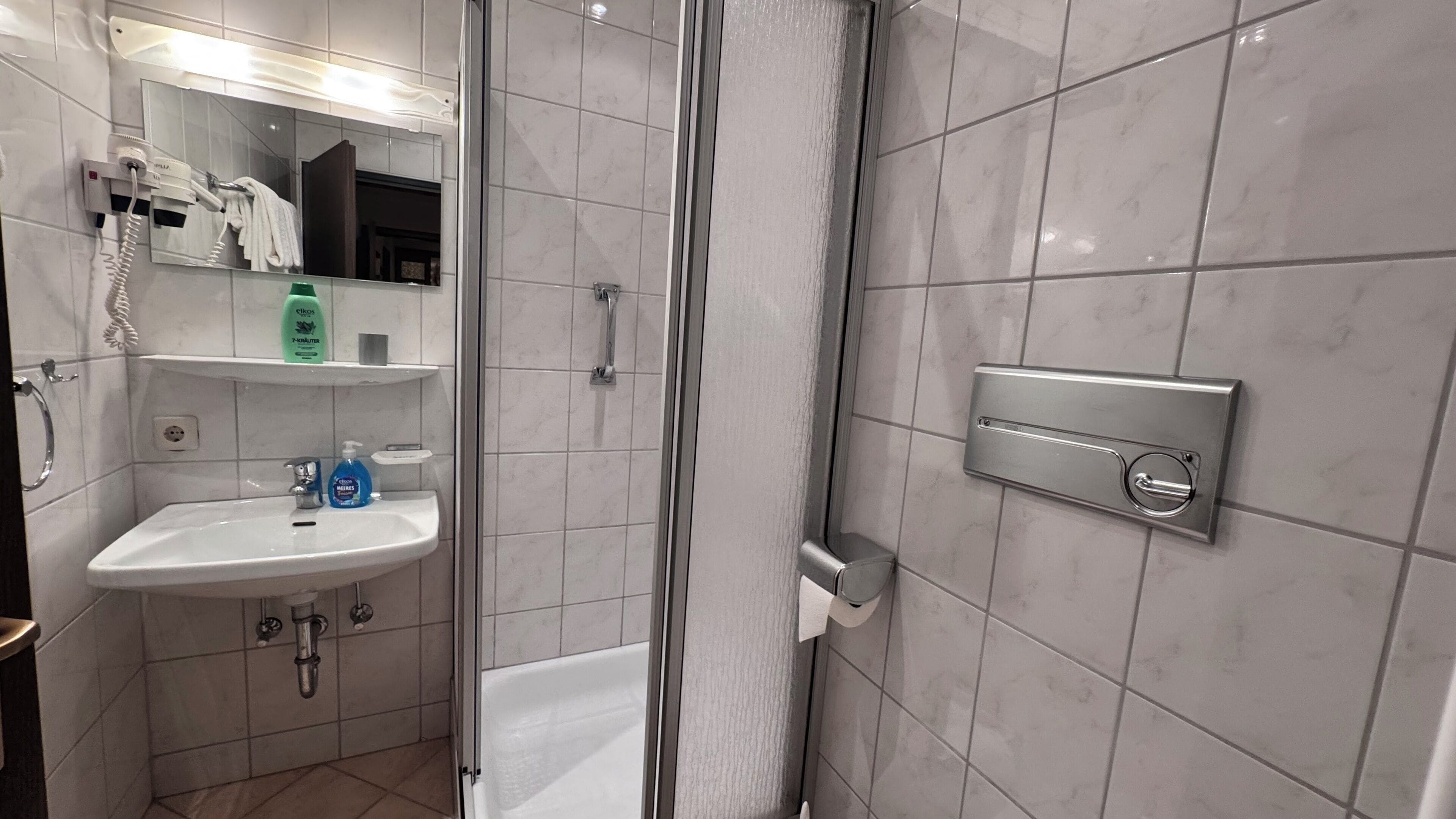 A modern bathroom with a white sink, a glass shower enclosure, and a towel rack.