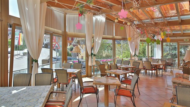 A restaurant with outdoor seating, large windows, and a wooden ceiling. - Hotel Restaurant Freihof (Oberharmersbach)
