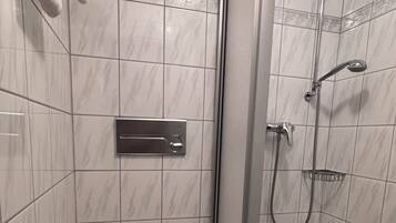 Ett badrum med toalett, dusch och handduksställ.