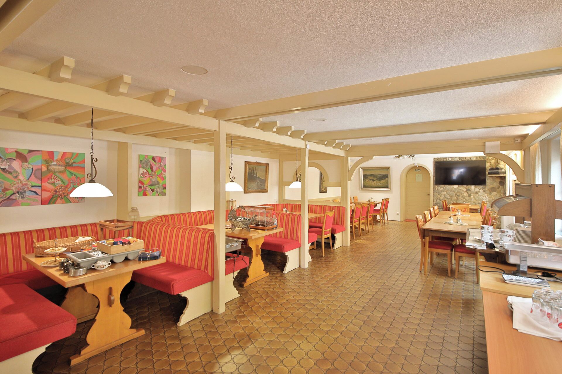 Un restaurant avec des banquettes et des tables, un sol carrelé et des œuvres d’art accrochées aux murs.