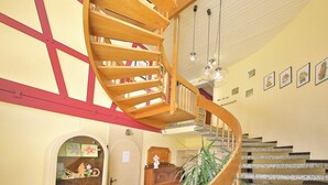 A spiral staircase with wooden railings and a granite floor, leading to a landing with a door and a small desk. - Hotel Restaurant Freihof (Oberharmersbach)