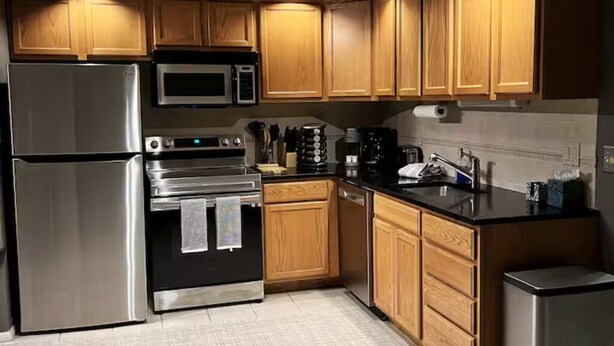 Una cocina moderna con armarios de madera, electrodomésticos de acero inoxidable y encimera negra.