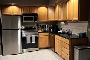 A modern kitchen with wooden cabinets, stainless steel appliances, and a black countertop.