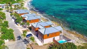 A coastal hotel with multiple buildings, a swimming pool, and a beach view.