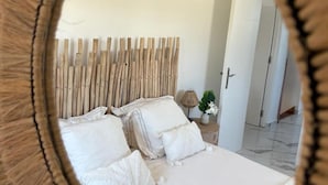 A bedroom with a bed, pillows, a nightstand, and a mirror.