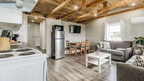 A modern kitchen with a stainless steel refrigerator, a stove, and a dining area with wooden chairs and a table. - Elegant home away from home - Valley View (Brooklyn)