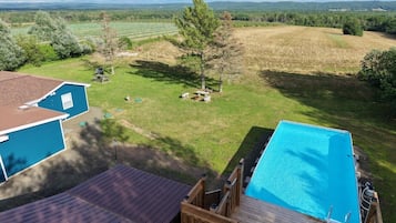 Ein Garten mit Schwimmbad, einer Holzterrasse und einem Haus.