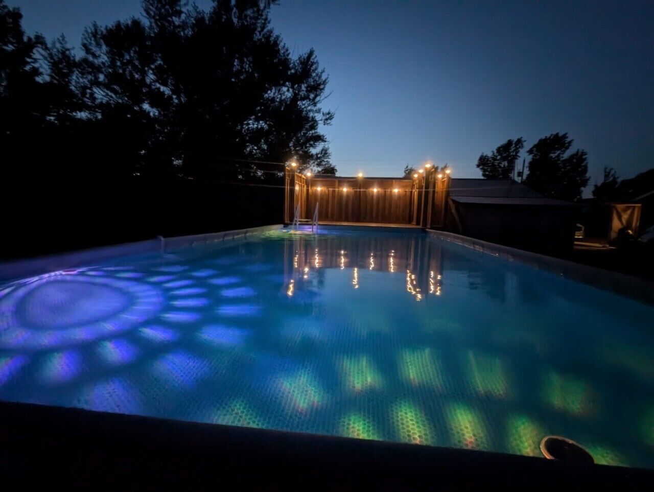 A swimming pool with a light-up feature at dusk.