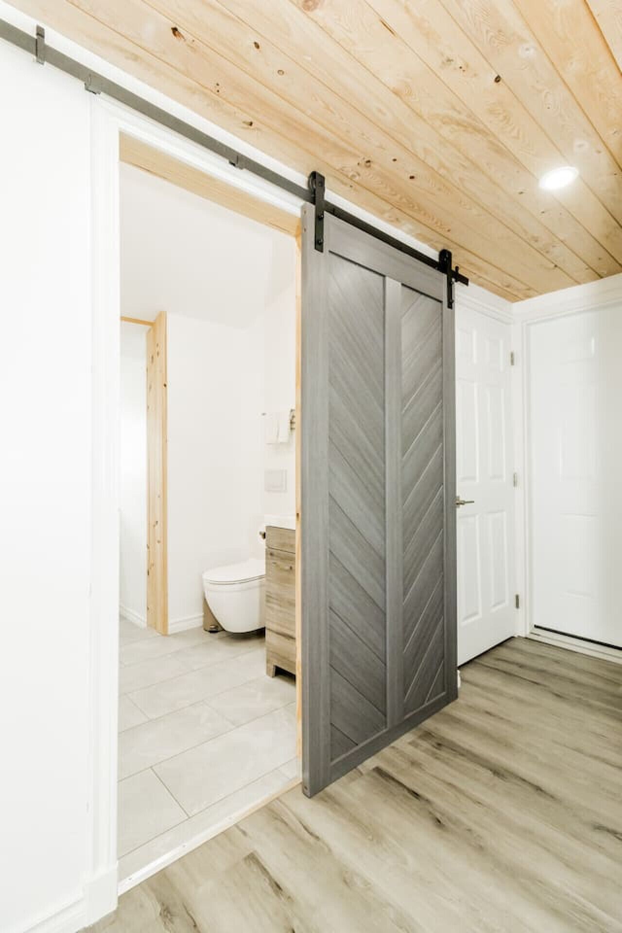 A room with a sliding barn door, a toilet, and a sink.