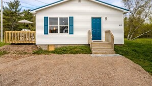 A single-story house with a blue door and shutters, a small porch with steps, and a number 415 on the side.