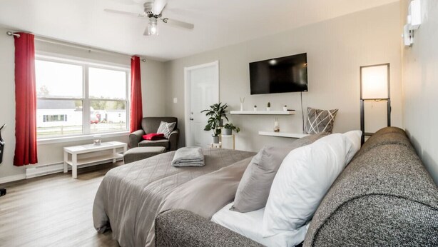 A modern hotel room with a large bed, a sofa, a desk, and a TV.
